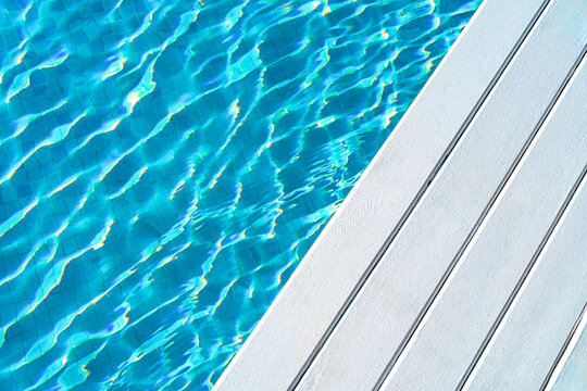 Sparkling blue pool water with sunlit ripples by deck