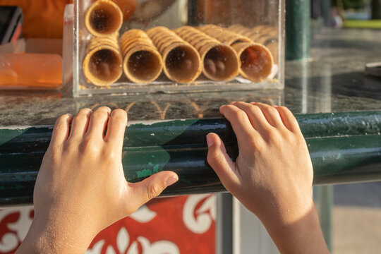 Child's hands reaching for ice cream cones at stand
