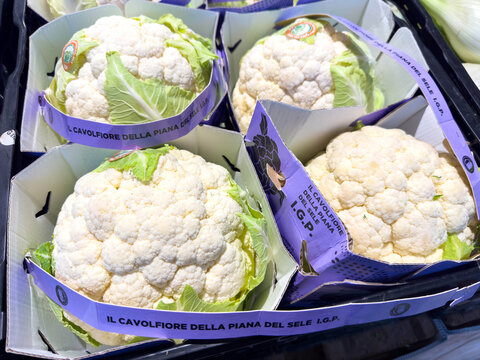 Venice, Italy - February 14, 2026: Fresh cauliflowers with labels in cardboard boxes displayed at a market, showcasing Italian produce with visible branding and packaging
