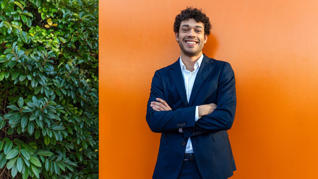 Confident professional smiling against orange wall