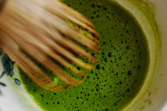 Vibrant matcha tea being whisked into frothy perfection