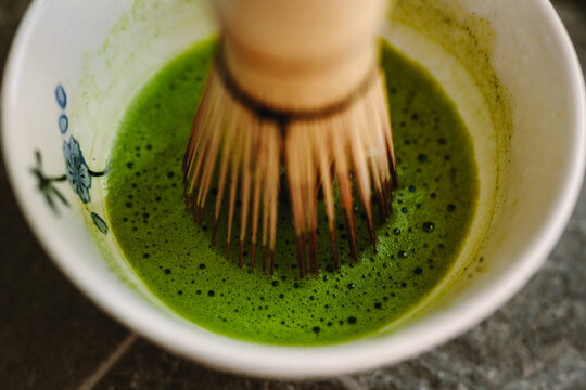Traditional matcha preparation with bamboo whisk