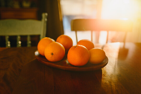 Bowl of fresh oranges on a wooden table at sunrise