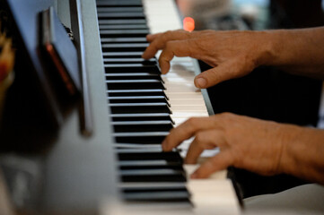 Fototapeta premium Close-up of male hands playing the keys of a digital piano
