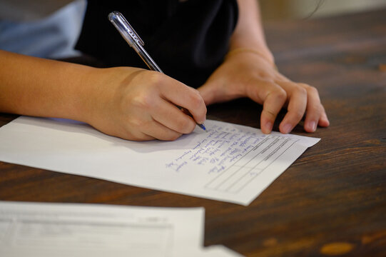 Close-up of hands filling out an official form