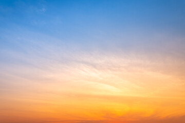 Fototapeta premium Beautiful sunrise sky with vibrant gradient orange and gold colors and soft blue, Clear atmosphere with wispy clouds. Peaceful, perfect for background and copy space, High resolution images
