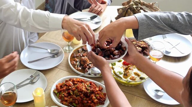 high angle of hands giving and receiving a plate of dates fruit for at iftar time on ramadan kareem.