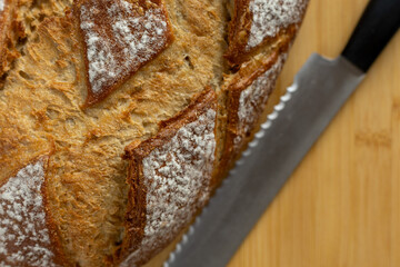 rustic sourdough bread with bread knife on cutting board close-up