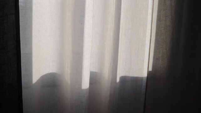 Soft sunlight patch from a window on white linen curtain. Bright natural light and delicate fabric texture create a calm, minimal interior atmosphere. Perfect airy lifestyle background.