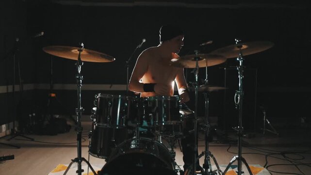 Shirtless rock drummer performing on stage