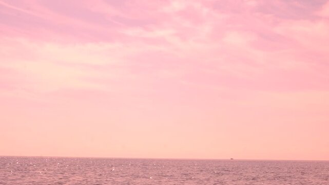 Alone sailboat floating in vast open sea under serene surreal pink sky, tranquil ethereal view, maritime. Dreamy wilderness. Blurred bleached effect, movie-like scene	