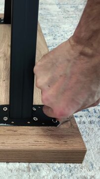 A man assembles furniture using a screwdriver