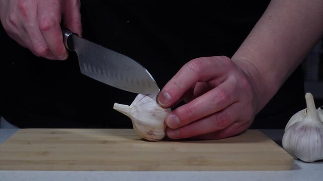Cutting the top off a whole garlic head close-up