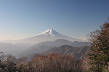 Fototapeta premium 雪化粧した富士山と重なる山並みの風景
