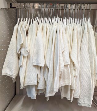 Camisetas de manda corta, de manga larga y sudaderas de color blanco en perchero de tienda de ropa 