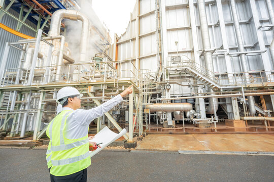 A male engineer stands working alongside a female engineer, communicating via radio in the power plant, overseeing heavy machinery and ensuring the reliability of the steam power system.