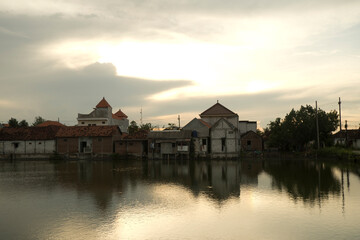 Obraz premium Peaceful Evening Landscape with Water Pond Between Houses