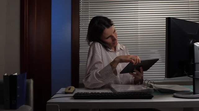 Woman juggling phone, tablet and keyboard at a cluttered desk, working late and multitasking under pressure to meet deadlinesproductivity, stress and modern office life