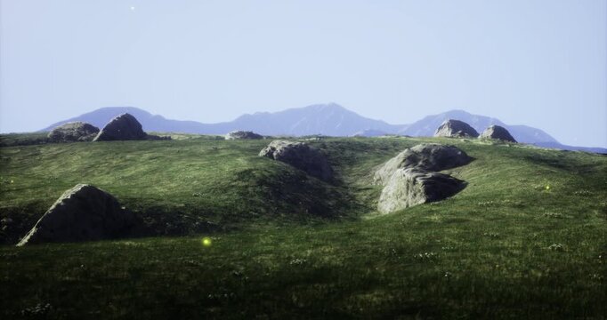 Expansive grassy terrain dotted with uneven rocks stretches towards distant mountains. A bright blue sky enhances the feeling of openness, inviting tranquility and reflection.