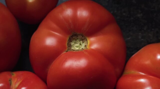 A ripe, red beefsteak tomato with deep ribbing and "catfacing" at the stem. This distorted growth creates a lumpy, multi-lobed shape. Its meaty texture makes it ideal for slicing and sandwiches.