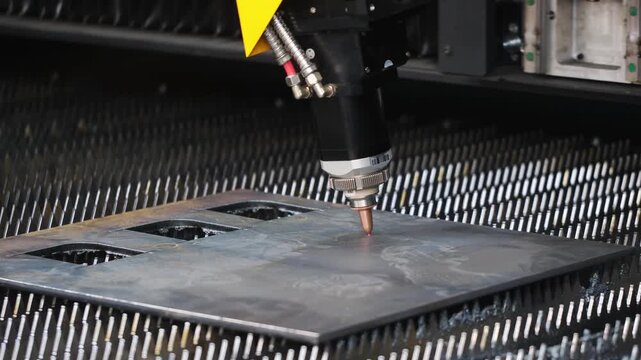 Close-up of fiber laser cutter nozzle and head assembly during high-speed sheet metal profile cutting on CNC flatbed table