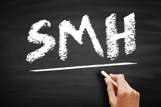 SMH text on blackboard. Popular social media acronym for shaking my head to express disappointment or disbelief. Hand with chalk on a textured slate surface