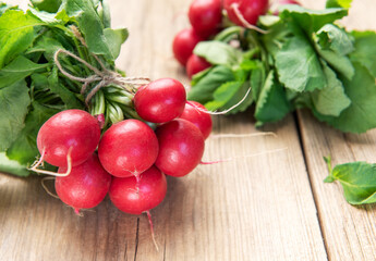Fresh organic radishes with green leaves on rustic wood