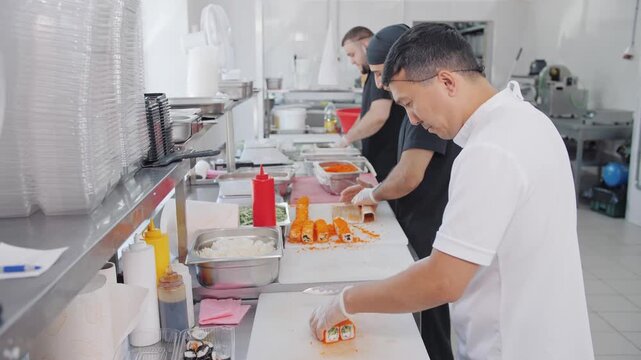Sushi roll assembly in a busy commercial kitchen.