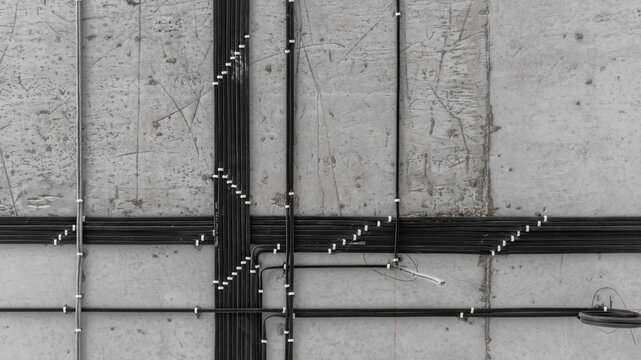 electrical installation work, cable laying. perfect wiring of cables on the ceiling. straight perpendicular lines. professional electrician, concrete slab, black and white cables, repair