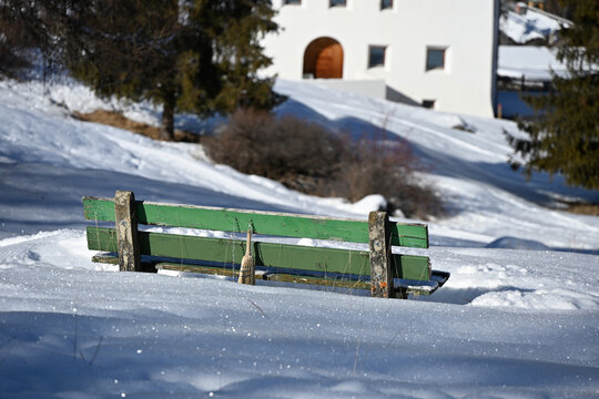 Green Wooden Bench Half Buried in Snow in Scuol, Swiss Alps