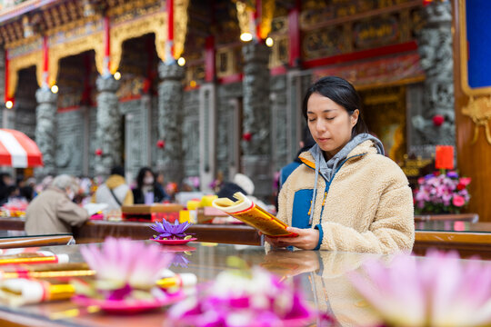 Female worshipper lighting incense stick at temple