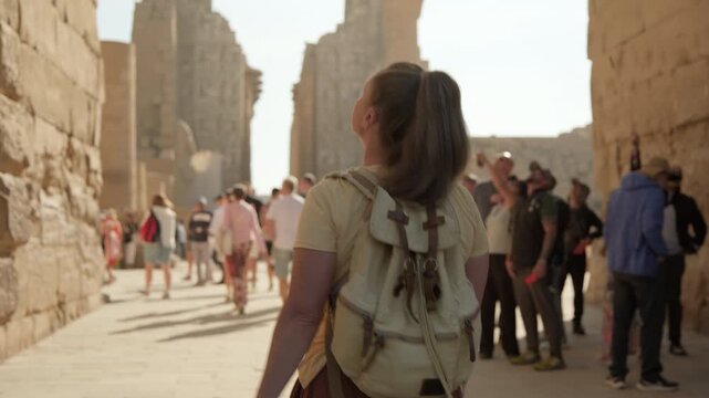 Woman tourist explores while walking among blurred crowd of people visiting ancient Karnak Temple, 