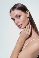 Stunning young woman exudes confidence with elegant pose against minimalistic background