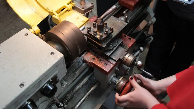 A person is operating a metalworking machine adjusting a tool with their hands