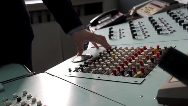 A person's hand is touching a control panel with many buttons