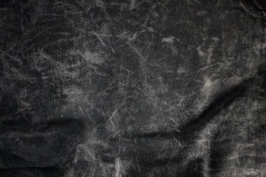 High resolution macro texture of faded dark grey washed denim fabric.