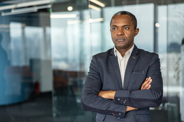 Fototapeta premium Confident executive man standing in a modern office building, representing leadership, professionalism, and corporate success while looking away with a thoughtful expression