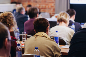 Obraz premium Conference, hall with audience, panel discussion at forum, people on a congress together listen to speaker on stage at convention, plenary session at business lecture seminar, venue for presentation