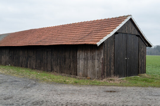 Long wooden barn with red tile roof