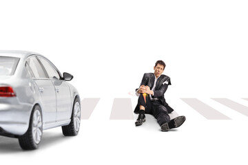 Fototapeta premium Injured man in a torn suit sitting on a crosswalk