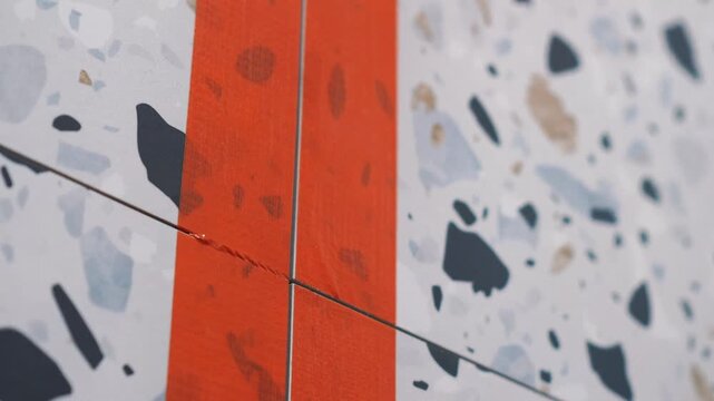 Master tiler cuts tape with a clerical knife and prepares tile seams before epoxy grouting. preparatory work, professional tile work, grouting, epoxy grout, grouting, bathroom renovation