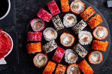 different delicious sushi rolls set with fish served at black dish  at black table. flat lay. close up