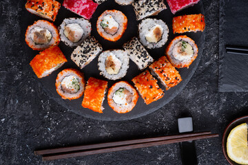 different delicious sushi rolls set with fish beautiful served at black dish at black table. flat lay. close up