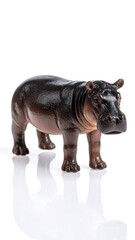 Obraz premium A brown toy hippopotamus stands on a glossy white surface, casting a reflection
