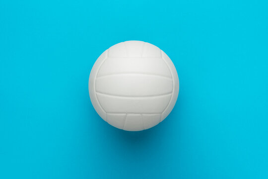Top view photo of white volleyball ball as volleyball concept . Minimalist flat lay image of leather volleyball ball over blue turquoise background with copy space and central composition.