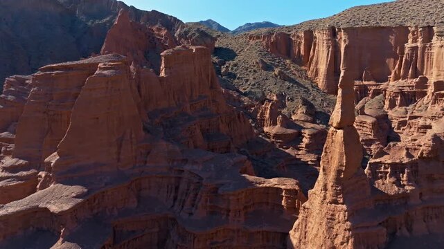Drone flying forward between majestic eolian rock formations in arid desert landscape of Kyrgyzstan