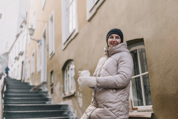 Obraz premium Woman enjoys winter weather while standing on a narrow street with old buildings in the background