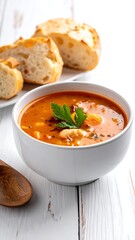 Hearty soup with bread, presented in a white bowl on a rustic white wooden table