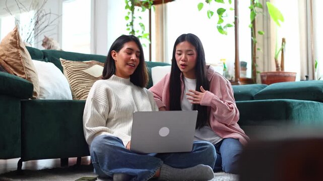 Two female friends using laptop computer at home