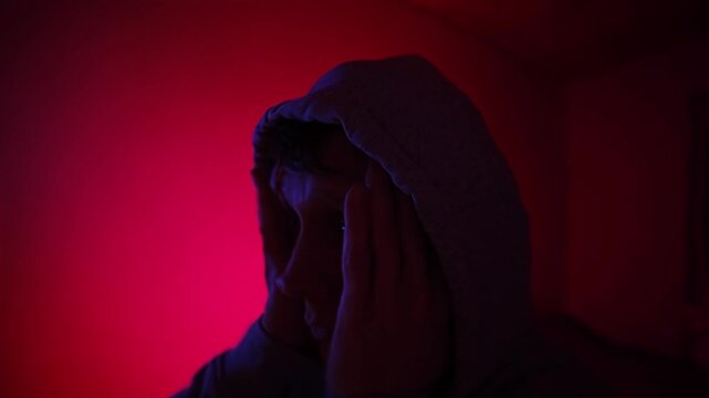 Drug abuse and psychological deterioration shown through red and blue light, man losing self control and connection to reality, visual metaphor of addiction, social collapse and mental crisis